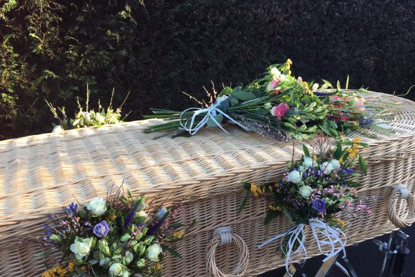 A wicker coffin decorated with flowers by the team at Full Circle Funerals
